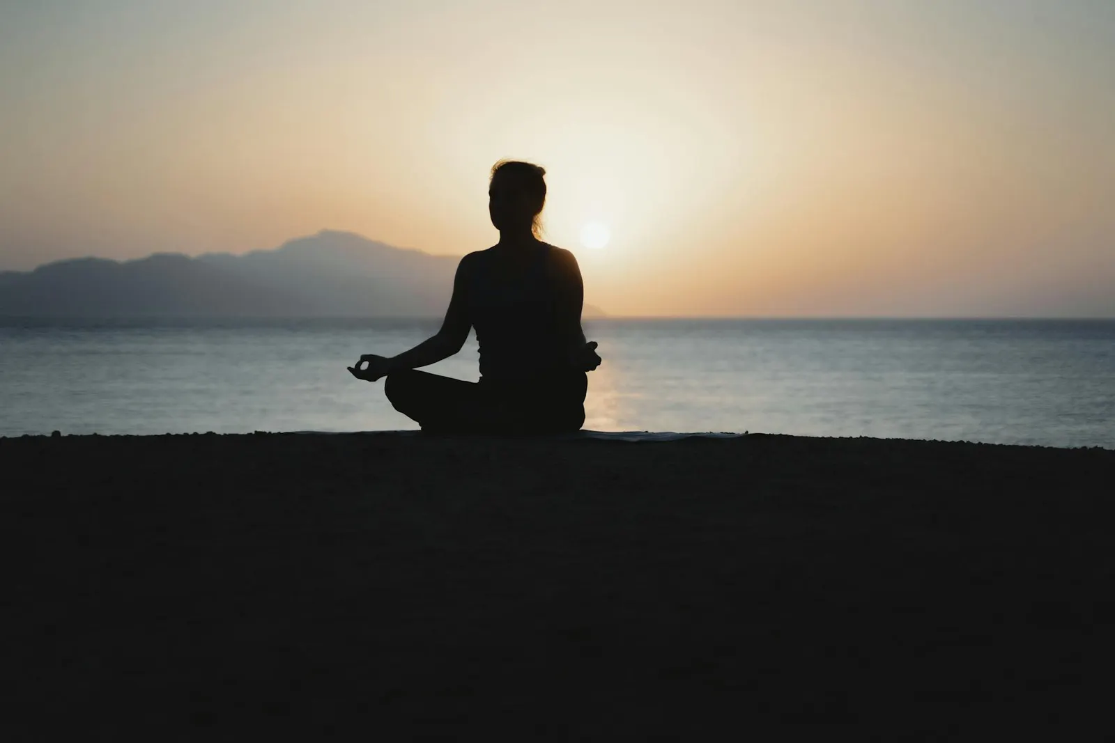 Silueta en meditación frente al mar al atardecer